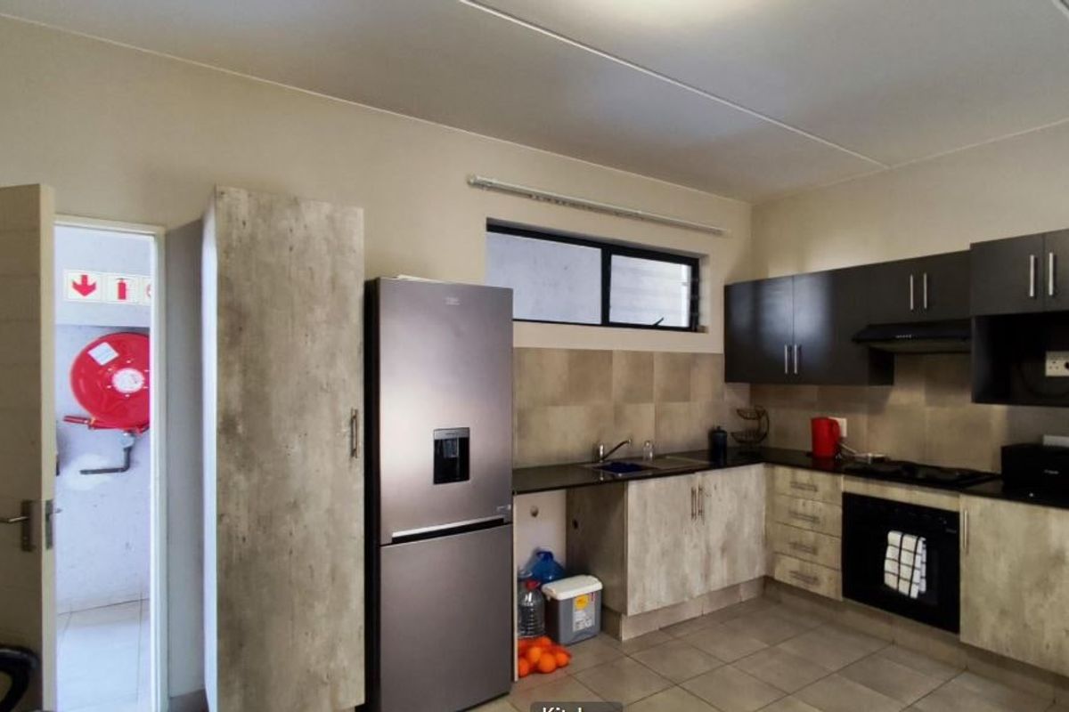 Modern kitchen featuring built-in cabinetry, laminate countertops, integrated oven, hob, extractor fan, and tiled backsplash with neutral finishes.