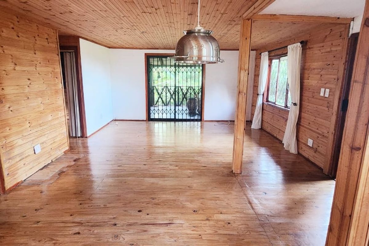 Spacious living area featuring extensive timber wall and ceiling paneling, polished timber flooring, and a security gate leading to the exterior.