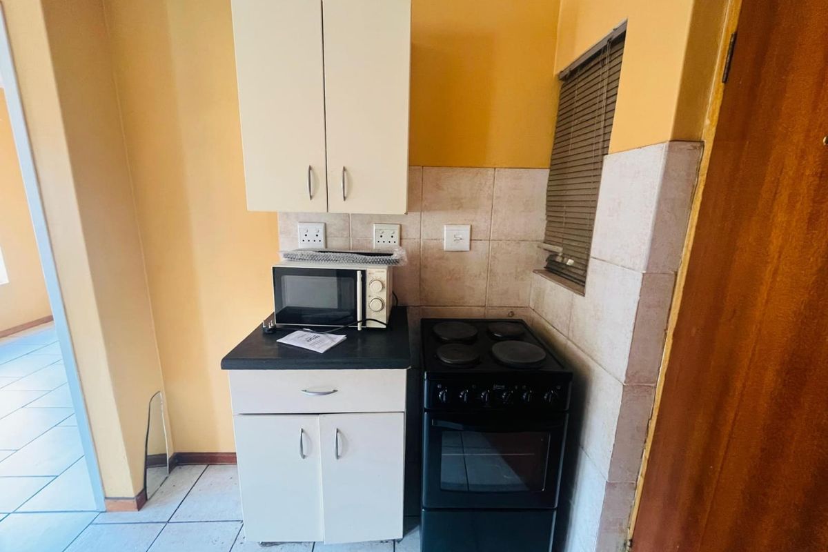 Compact kitchen area featuring built-in cabinetry, tiled backsplash, and a freestanding electric stove with oven.