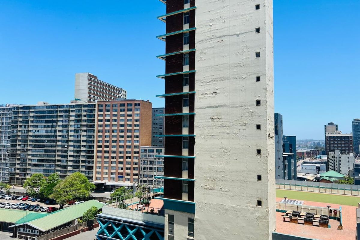 An elevated view of a high-rise apartment building facade showing significant exterior paint wear and structural weathering in an urban setting.