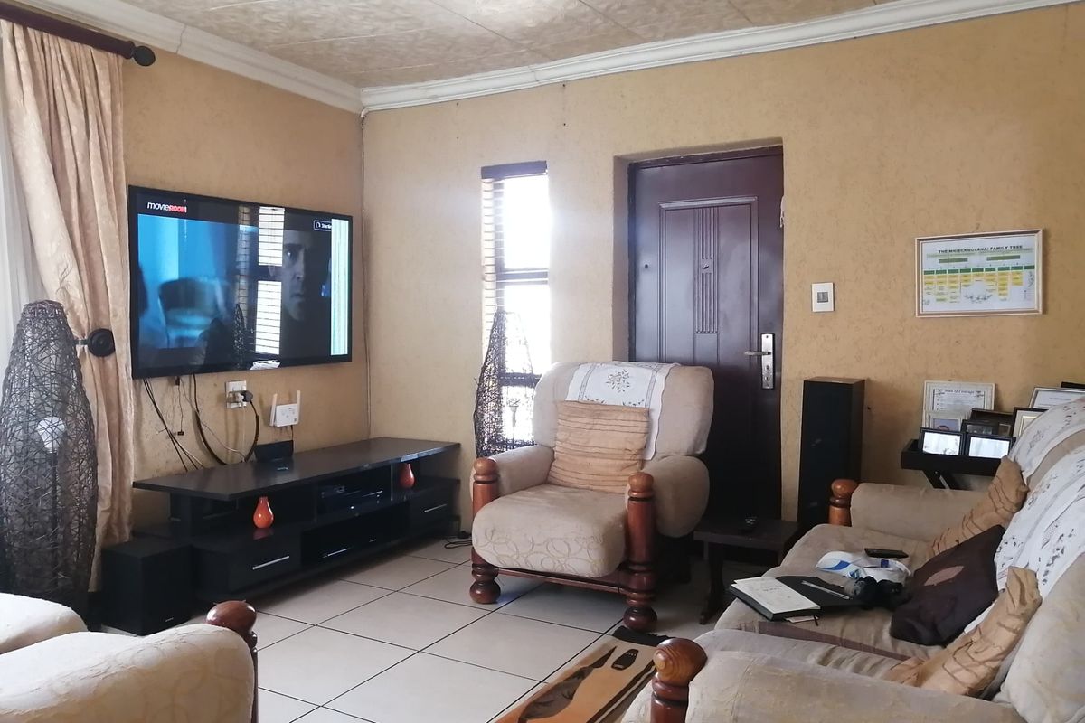 A comfortable living room featuring tiled flooring, textured wall finishes, and a coved ceiling, providing a functional and lived-in space.