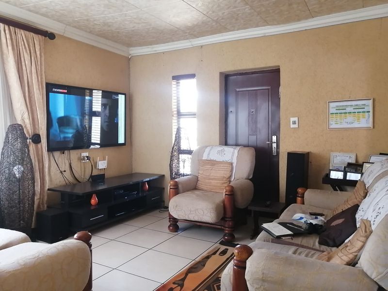 A comfortable living room featuring tiled flooring, textured wall finishes, and a coved ceiling, providing a functional and lived-in space.