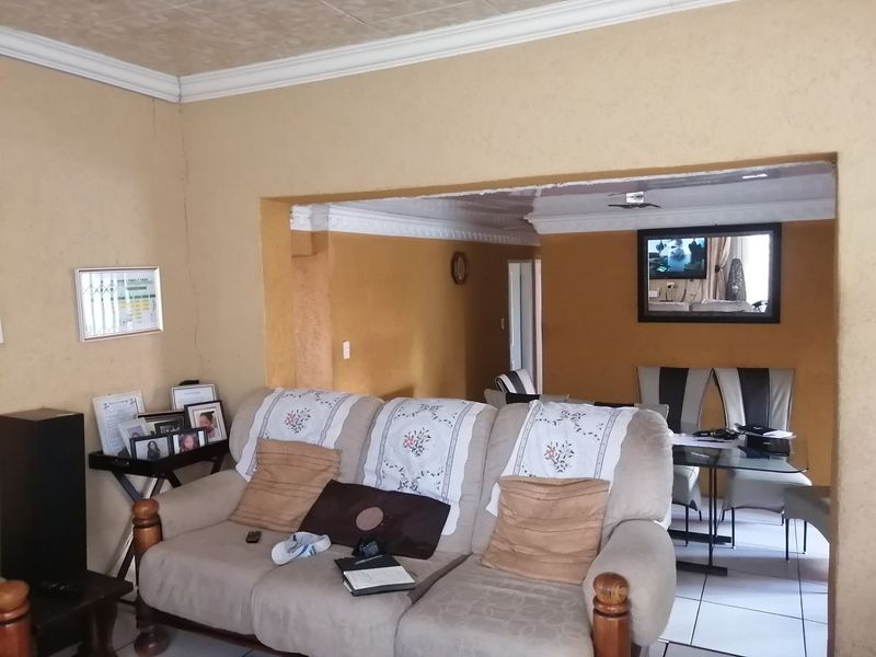 Open plan living and dining area featuring tiled flooring and decorative ceiling cornices, requiring cosmetic updates to improve the overall aesthetic.