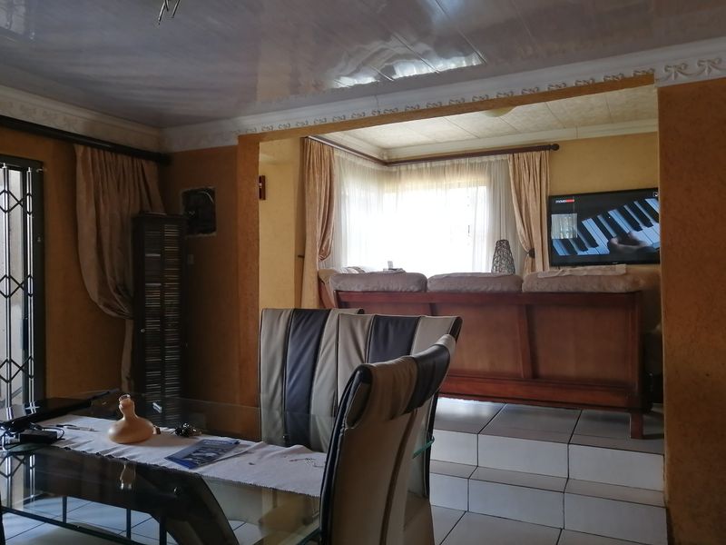 Open plan living and dining area featuring tiled floors, a raised platform section, and decorative ceiling cornicing.