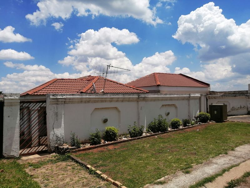 Front exterior view of the property featuring a tiled roof and a perimeter wall with visible signs of weathering and cracking.