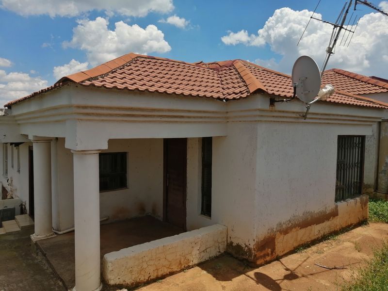 Front elevation of a single-story house featuring a tiled roof, covered porch with concrete columns, and security gates on windows.