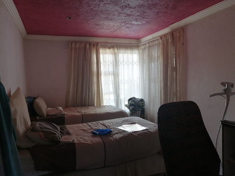 A bedroom featuring a textured ceiling, recessed lighting, and large windows with security gates, offering potential for cosmetic updates to improve the space.