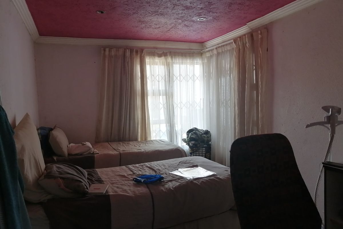 A bedroom featuring a textured ceiling, recessed lighting, and large windows with security gates, offering potential for cosmetic updates to improve the space.