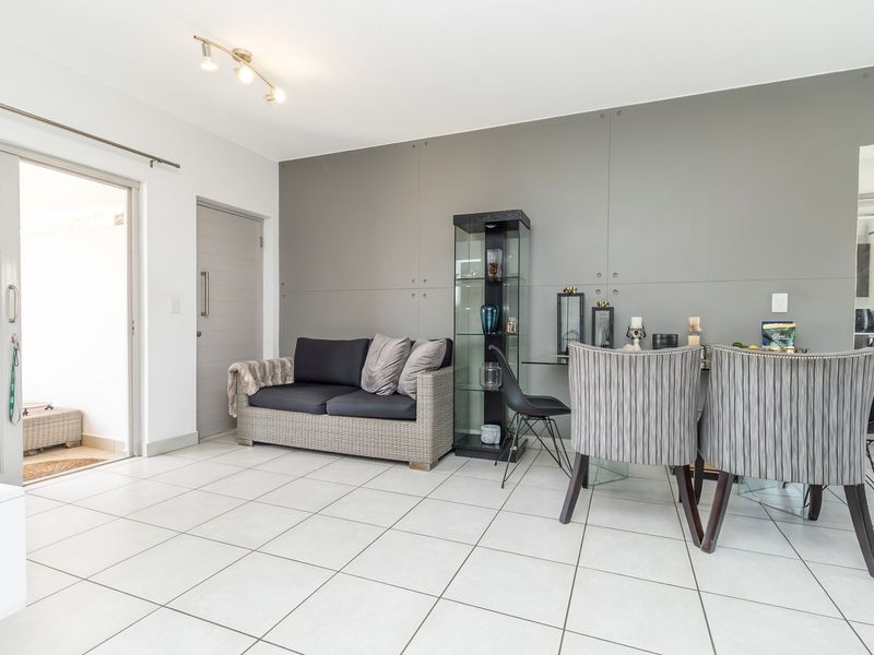 Open plan living and dining area featuring neutral tiled flooring, a modern grey panelled feature wall, and direct access to an outdoor patio.