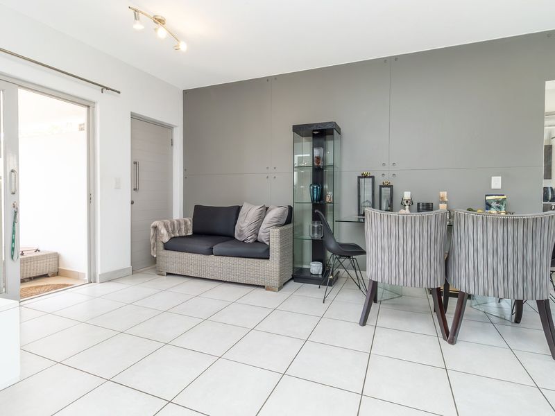 A bright living area featuring tiled flooring, a modern feature wall, and a sliding glass door providing access to an outdoor space.