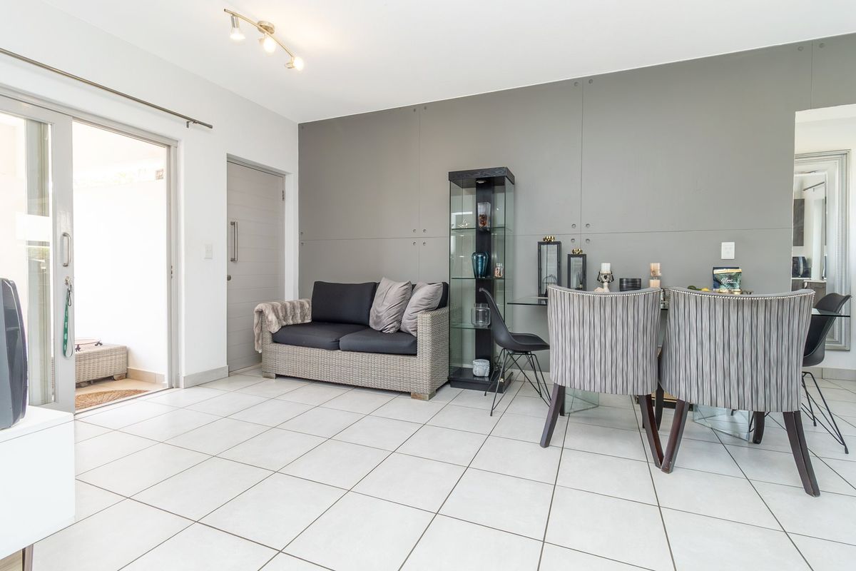 A bright living area featuring tiled flooring, a modern feature wall, and a sliding glass door providing access to an outdoor space.