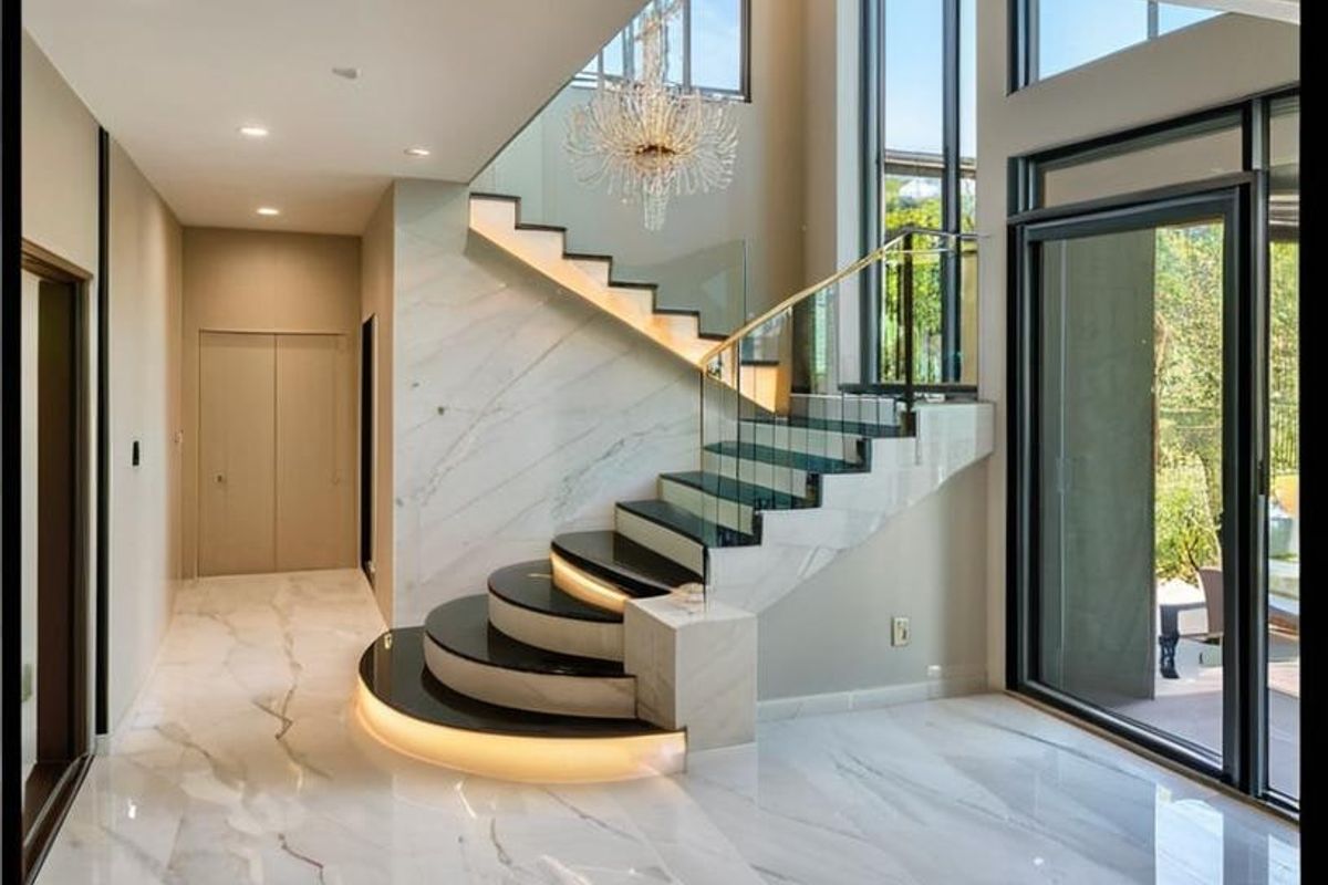 Grand entrance foyer featuring polished marble flooring, a striking floating staircase with integrated LED lighting, and expansive floor-to-ceiling windows.