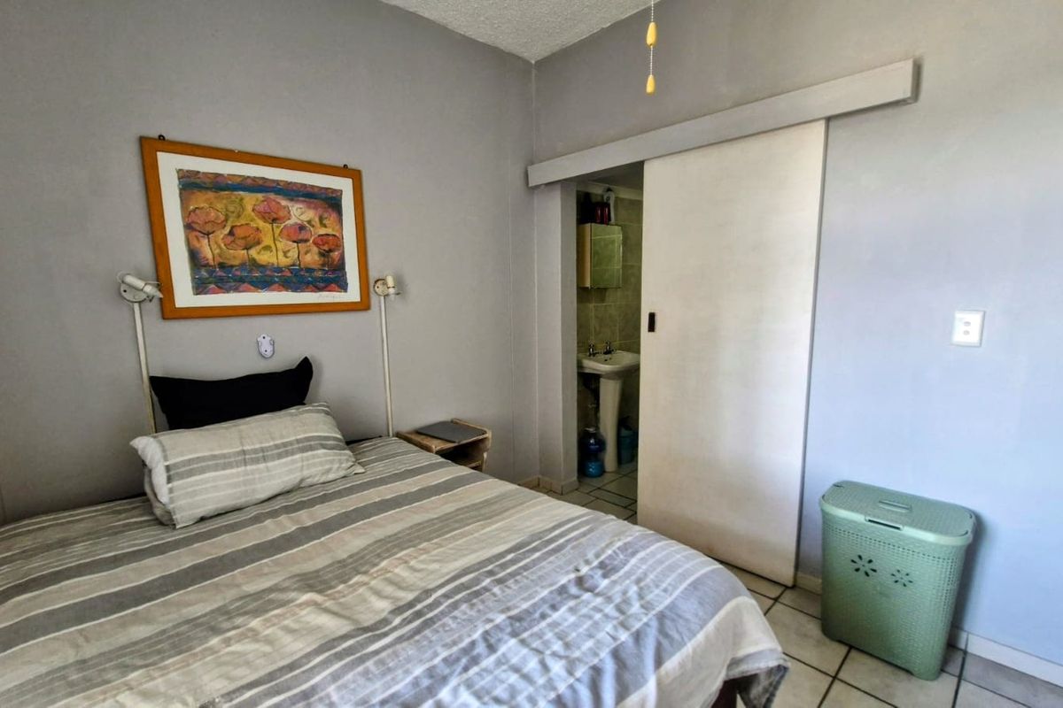 A bedroom featuring tiled flooring, a ceiling fan, and an en-suite bathroom accessed via a sliding door.