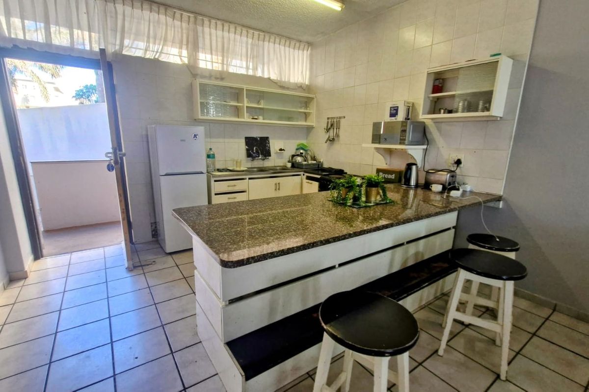 Functional kitchen featuring a granite breakfast bar, tiled backsplash, and ample built-in cabinetry, with direct access to an outdoor patio area.