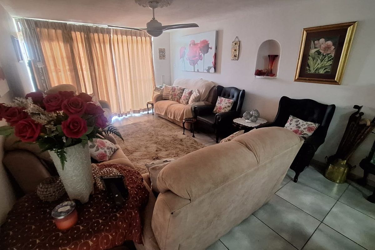 A comfortable living room featuring tiled flooring, a ceiling fan, and a recessed wall niche, with access to a balcony through sliding glass doors.
