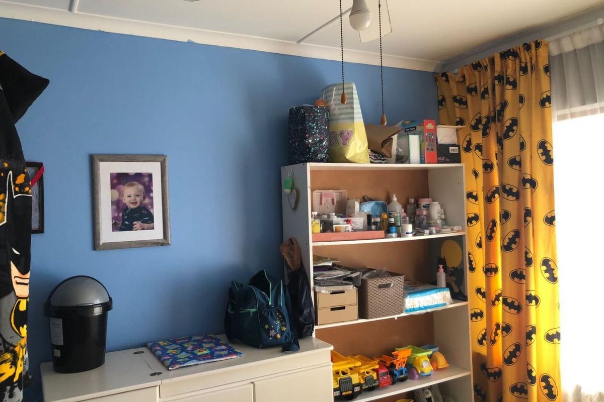 A bedroom featuring blue painted walls, a ceiling fan, and a window with curtains.