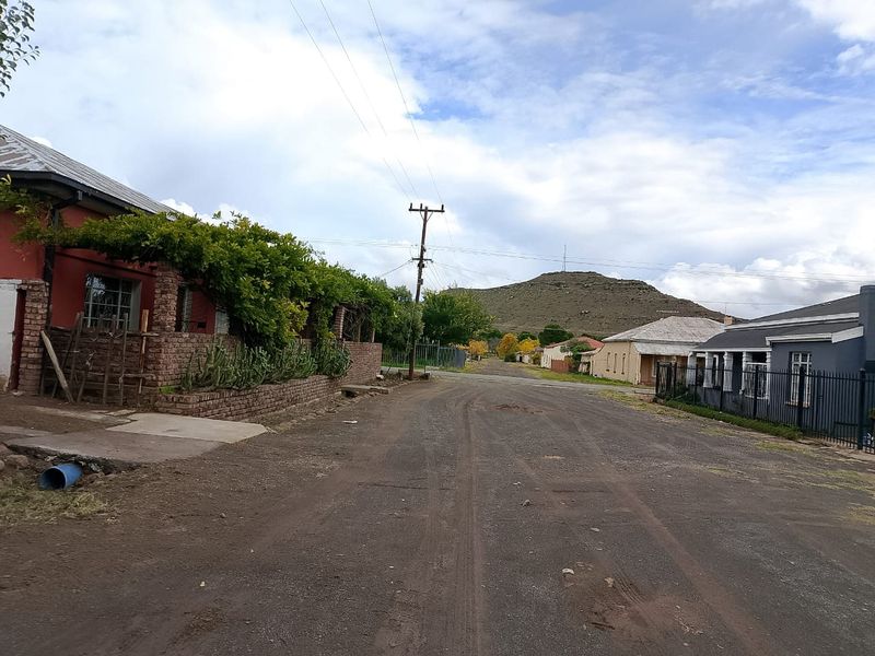 A street view showing the residential neighbourhood approach with a view of the surrounding landscape and local housing architecture.