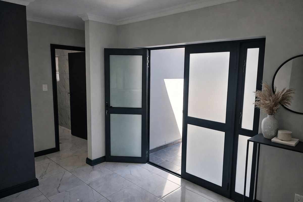 Modern living area featuring high-quality marble-look floor tiles, coving, and contemporary frosted glass double doors leading to an outdoor space.