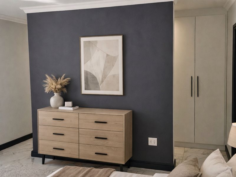 A modern, well-maintained bedroom featuring a dark accent wall, built-in cabinetry, and recessed lighting, creating a sophisticated and comfortable living space.