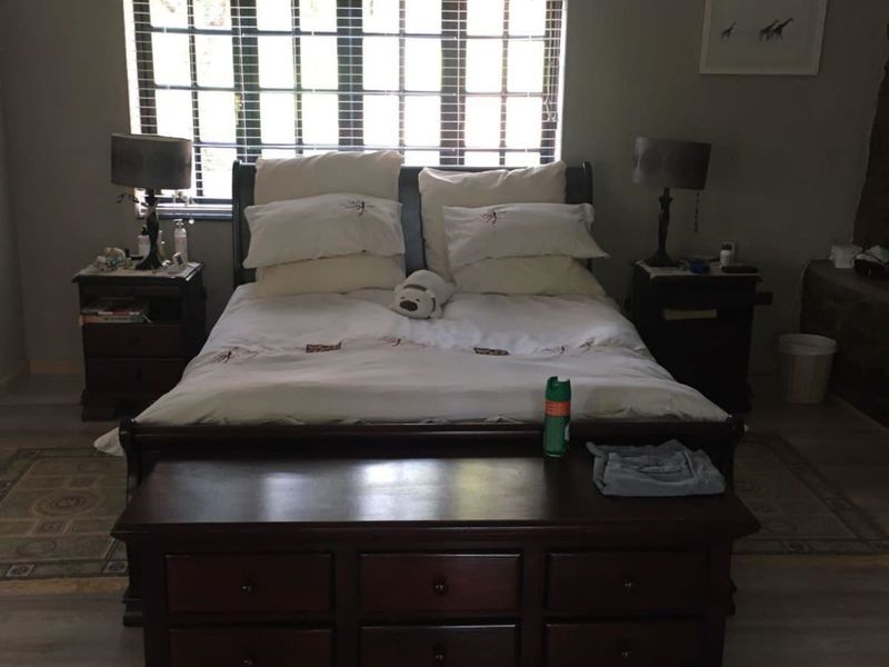 A bedroom featuring laminate flooring and a window with fitted blinds, providing a functional sleeping space.