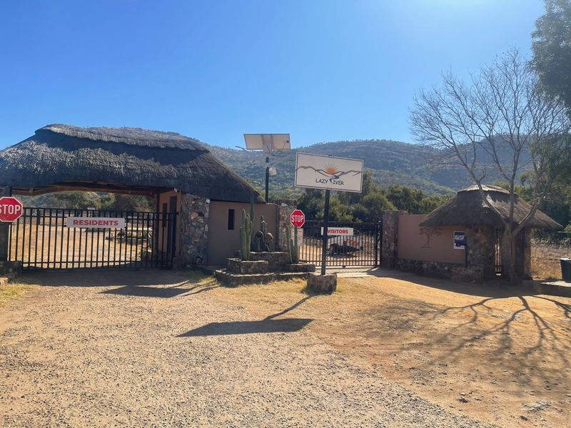 Entrance gatehouse to the property featuring traditional thatched roofing, stone masonry accents, and secure access control points.