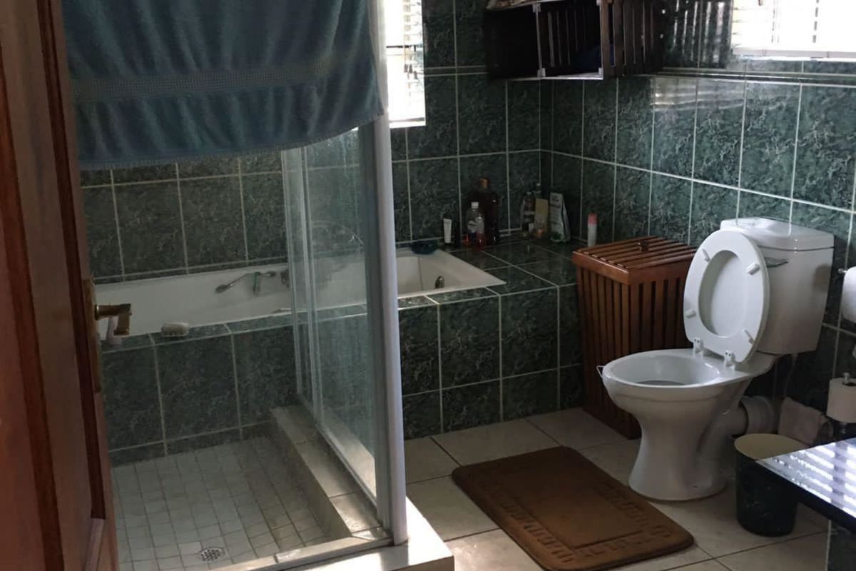 A functional bathroom featuring a built-in bathtub, a separate glass-enclosed shower, and tiled finishes throughout.