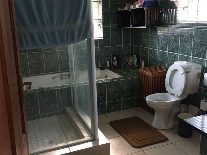 A functional bathroom featuring a built-in bathtub, a separate glass-enclosed shower, and tiled finishes throughout.