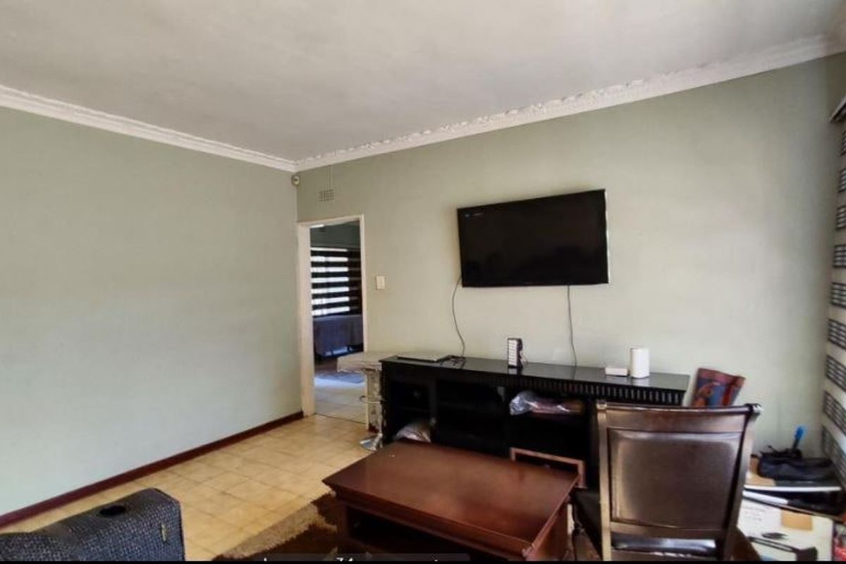 A living room featuring tiled flooring, crown molding, and roller blinds, providing a functional space with neutral wall tones.