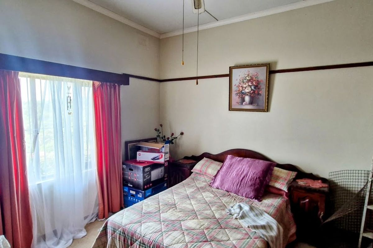 A bedroom featuring a ceiling fan, picture rail detailing, and natural light from a window with curtain tracks.