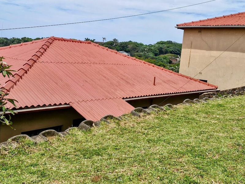 An elevated view of the rear property showing the roof structure, lawn area, and retaining wall boundary.