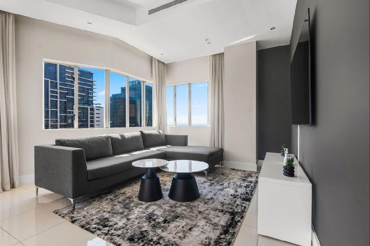 Modern living room featuring large windows with city views, tiled flooring, recessed ceiling lighting, and ducted air conditioning.
