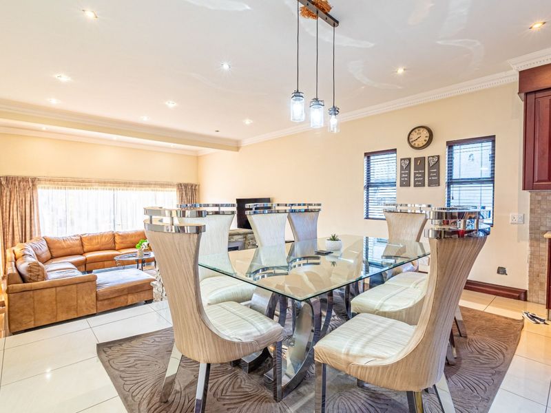 Open-plan living and dining area featuring tiled floors, recessed lighting, and a functional kitchen with dark wood cabinetry and mosaic backsplash.