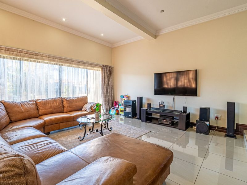 Spacious living room featuring large windows, polished porcelain floor tiles, and recessed downlighting, creating a bright and comfortable family entertainment area.