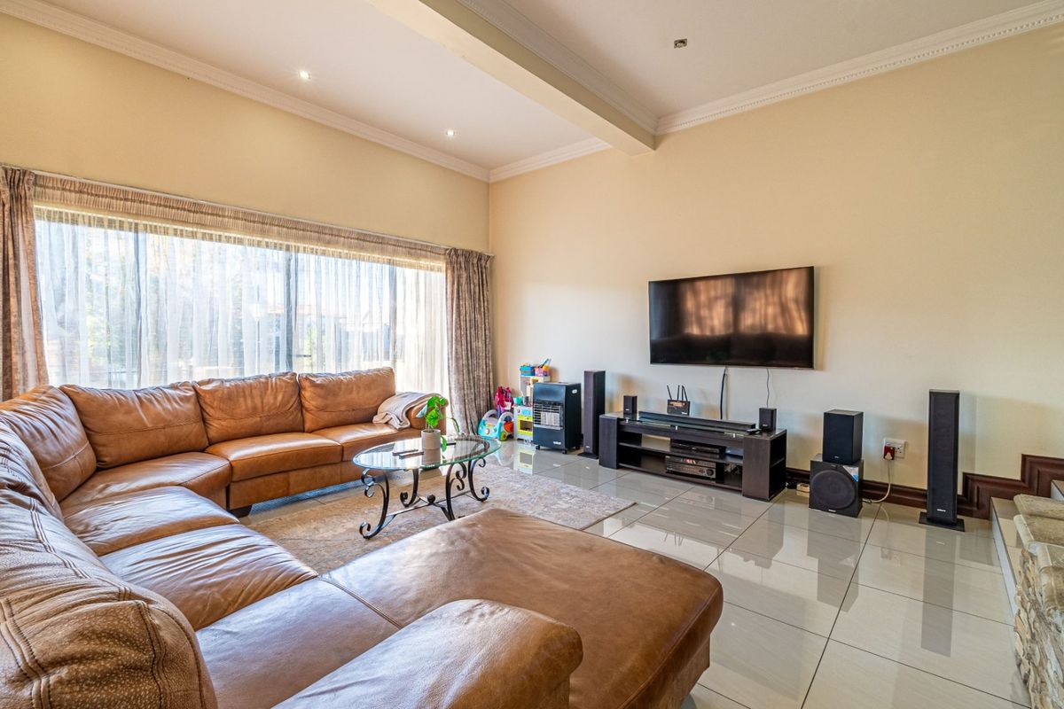 Spacious living room featuring large windows, polished porcelain floor tiles, and recessed downlighting, creating a bright and comfortable family entertainment area.