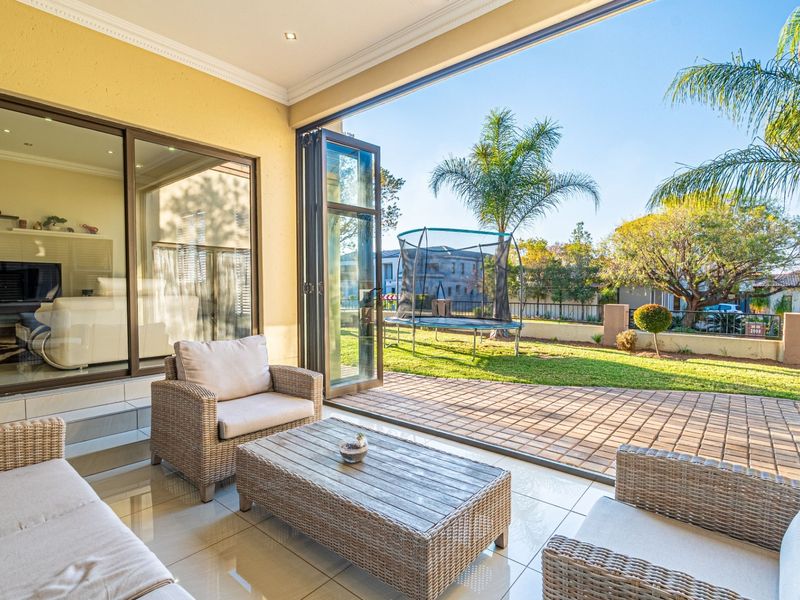 Covered patio area featuring tiled flooring and bi-fold doors that open seamlessly to the rear garden and paved outdoor space.