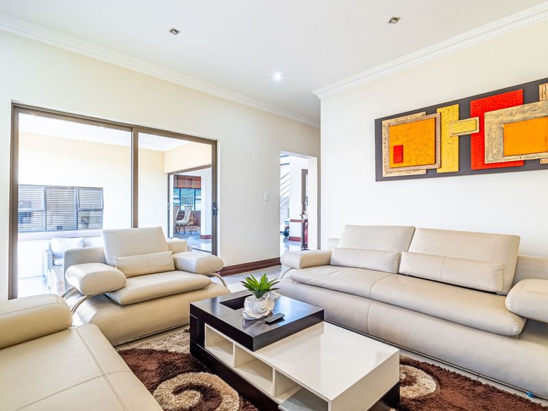 A bright and spacious living room featuring tiled flooring, crown molding, recessed lighting, and large sliding glass doors providing access to the patio.
