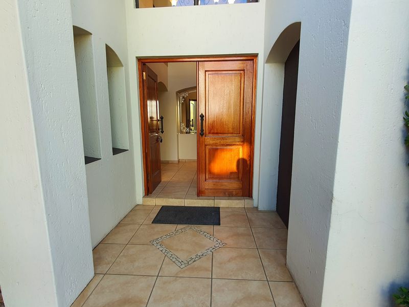 A welcoming front entrance featuring a double timber door, tiled porch area, and a high transom window allowing natural light into the foyer.