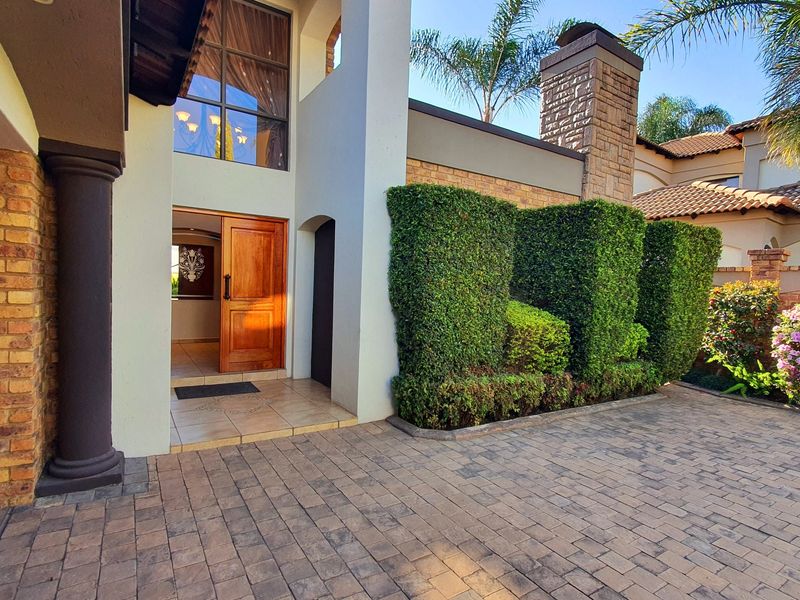 Attractive front entrance featuring a paved driveway, double volume facade, stone chimney detail, and a solid timber front door.