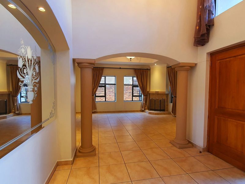 Spacious living area featuring tiled flooring, decorative columns, an elegant archway, and a built-in fireplace, offering a bright and open layout.
