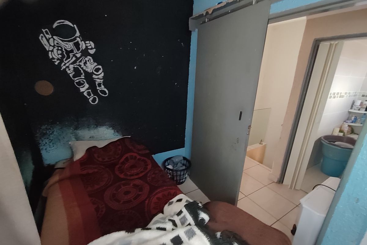 A bedroom featuring tiled flooring and a sliding door leading to an adjacent space, currently requiring cosmetic repairs and updates to finishes.