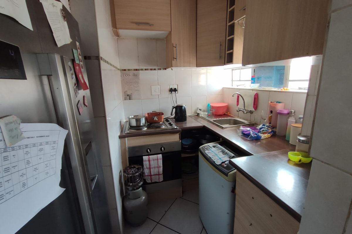 Compact kitchen featuring built-in cabinetry, laminate countertops, a stainless steel sink, and a built-in oven with gas hob.