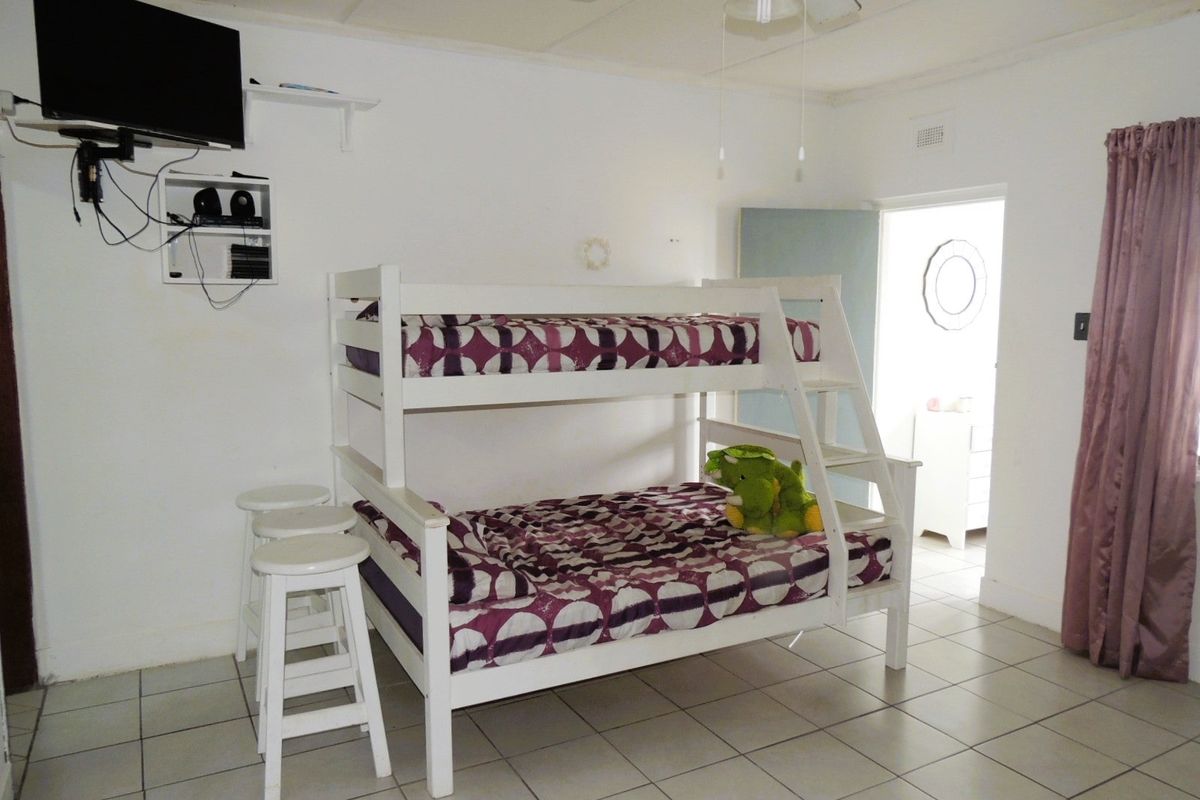A bedroom featuring tiled flooring and a ceiling fan, with access to an adjoining room.