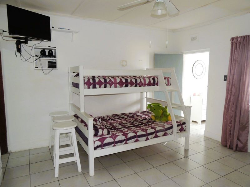 A bedroom featuring tiled flooring and a ceiling fan, with access to an adjoining room.