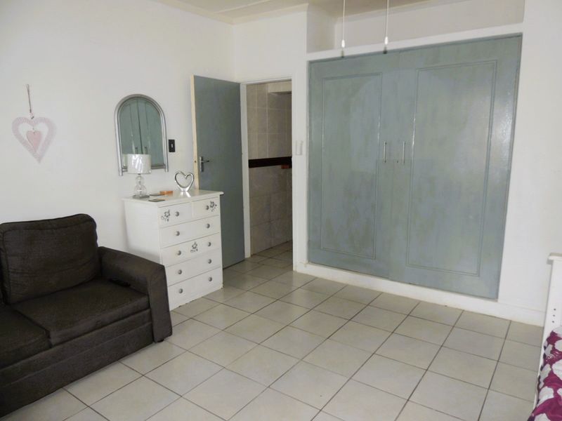 A bedroom featuring tiled flooring and a large built-in wardrobe with painted doors, providing direct access to an adjoining room.