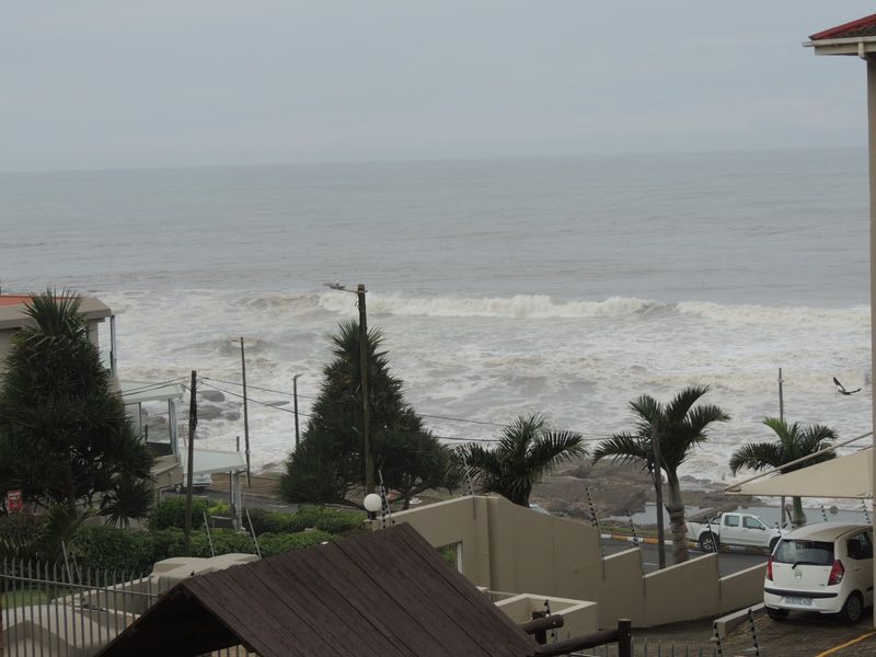 Elevated coastal view overlooking the ocean, featuring surrounding residential infrastructure, boundary walls, and electric fencing.