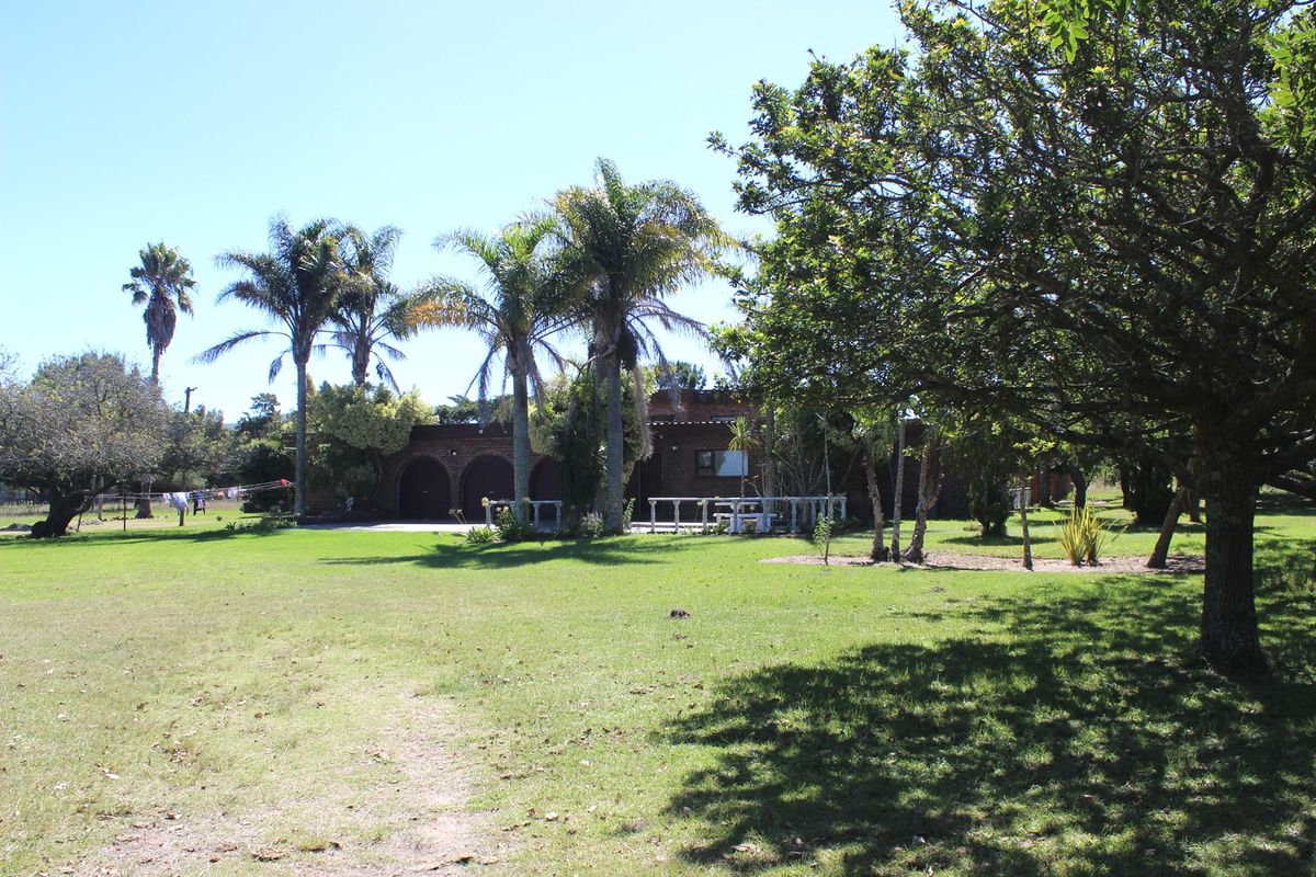 A view of the rear exterior of the farm property, featuring a brick facade with arched garage openings and a spacious surrounding garden.