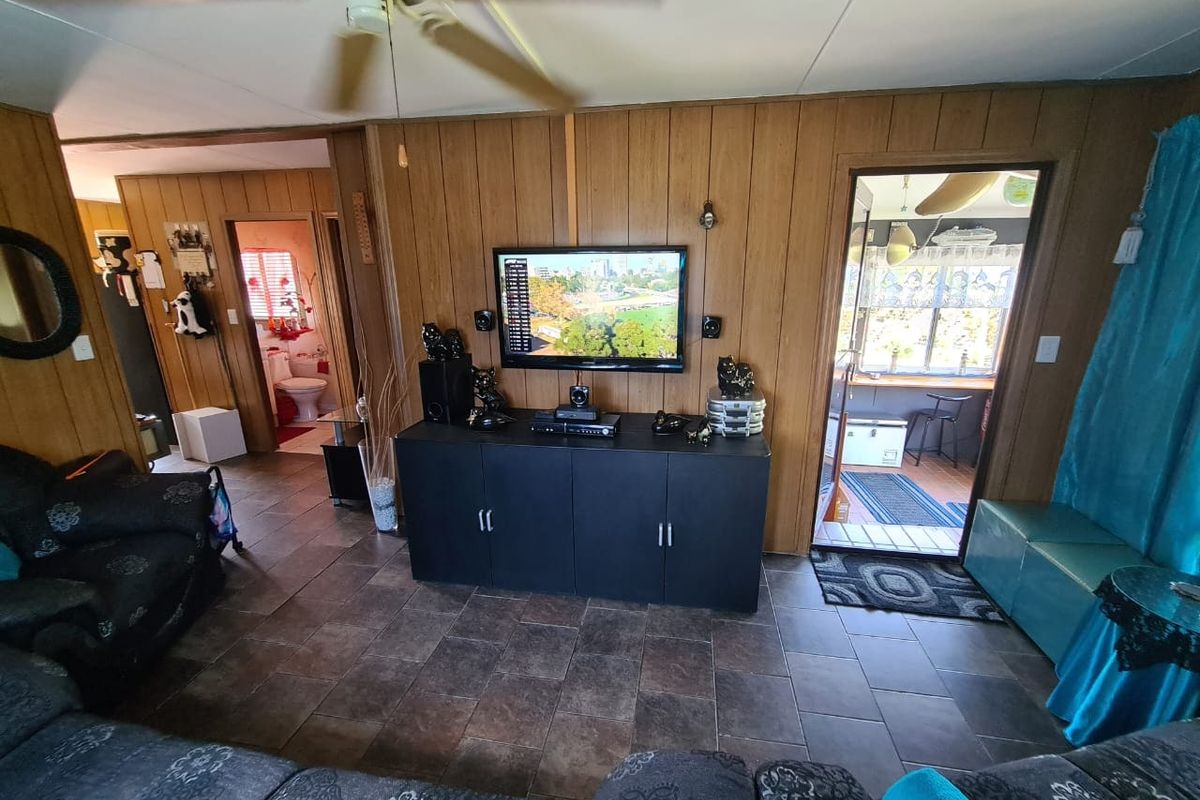 Living room featuring wood paneling, tiled flooring, and a ceiling fan, with direct access to an adjacent bathroom and patio area.