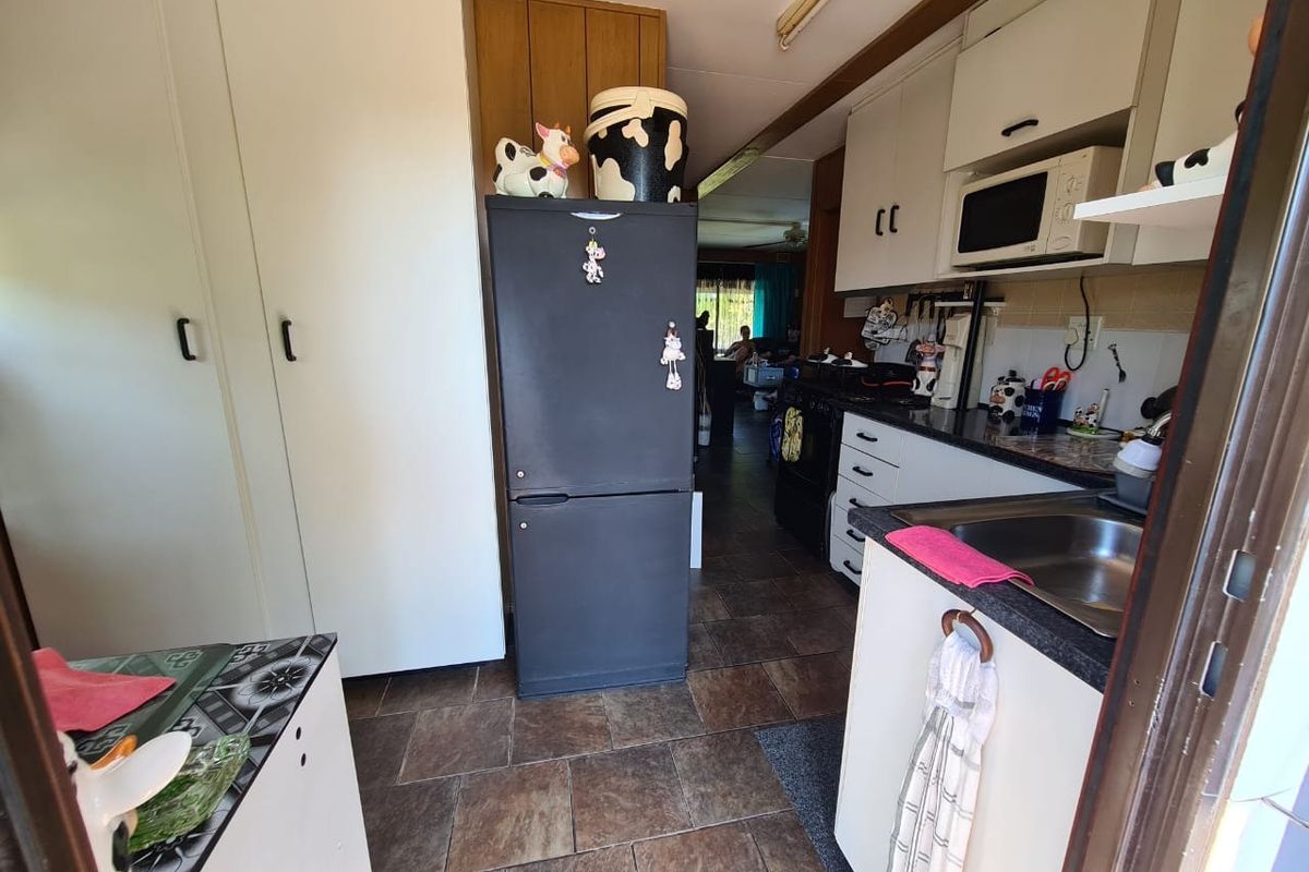 A functional kitchen featuring built-in cabinetry, laminate countertops, a stainless steel sink, and tiled flooring, offering a practical layout for daily meal preparation.