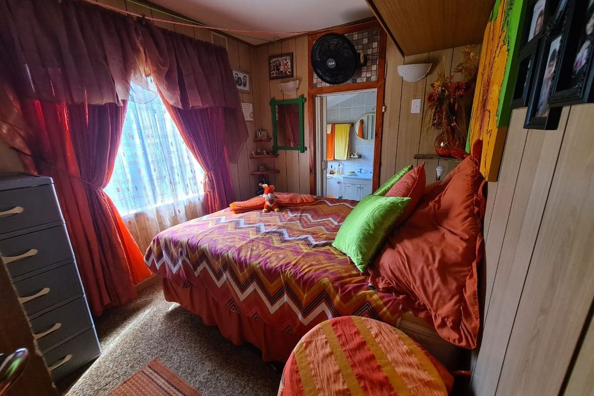 A bedroom featuring wood-paneled walls, carpeted flooring, and direct access to an en-suite bathroom.