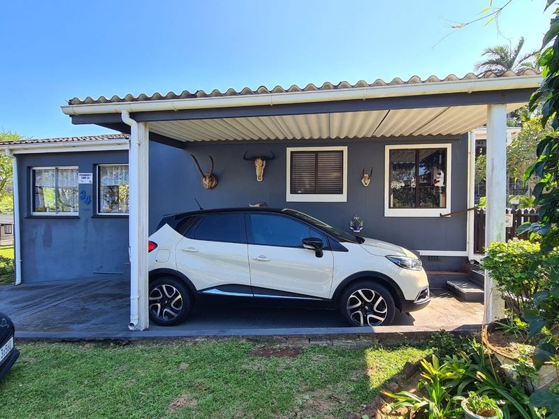 Front elevation of the townhouse featuring a covered carport, concrete driveway, and painted exterior walls with aluminium window frames.